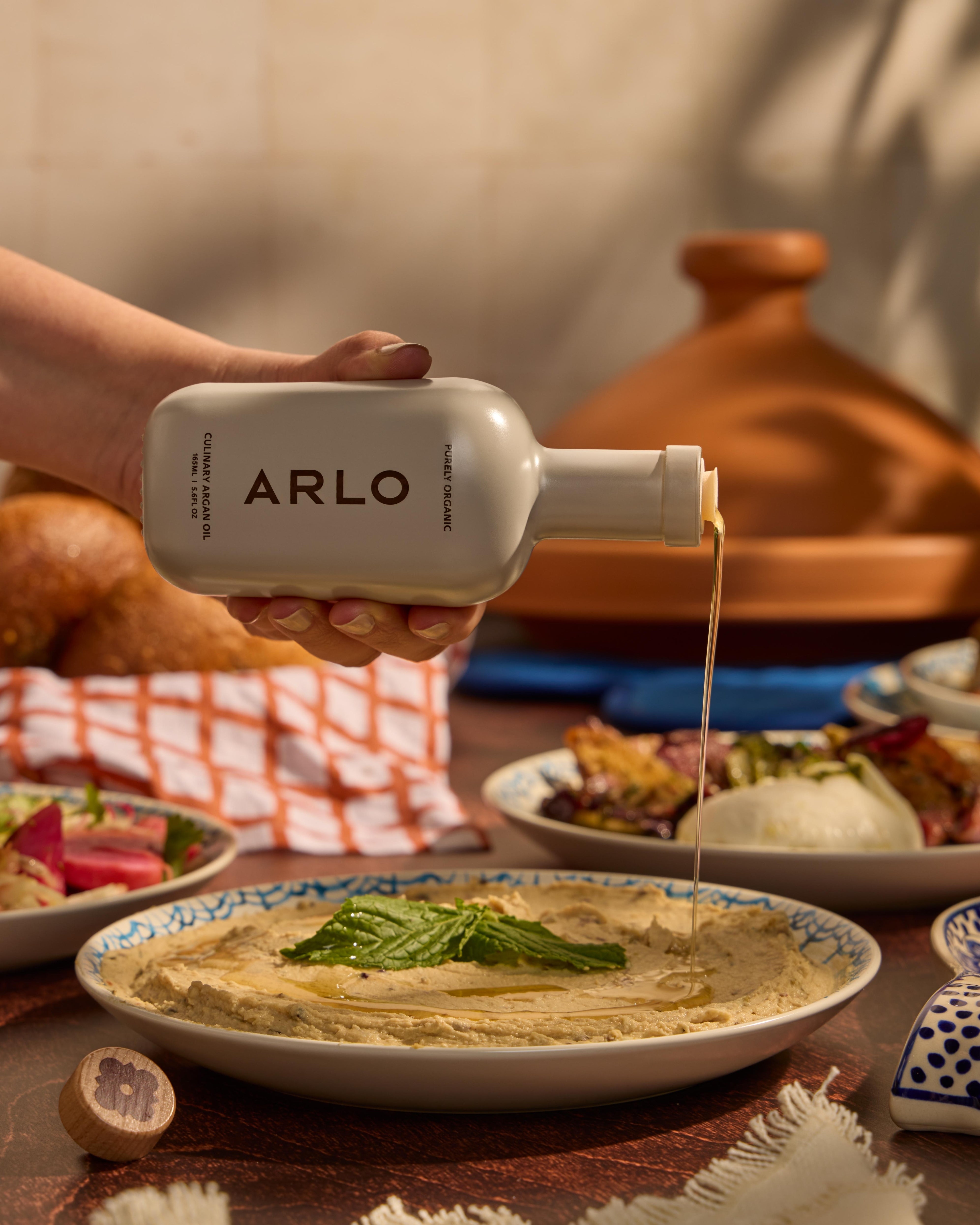 Drizzling ARLO Culinary Argan Oil over creamy hummus, showcasing premium Moroccan flavor in Mediterranean cuisine