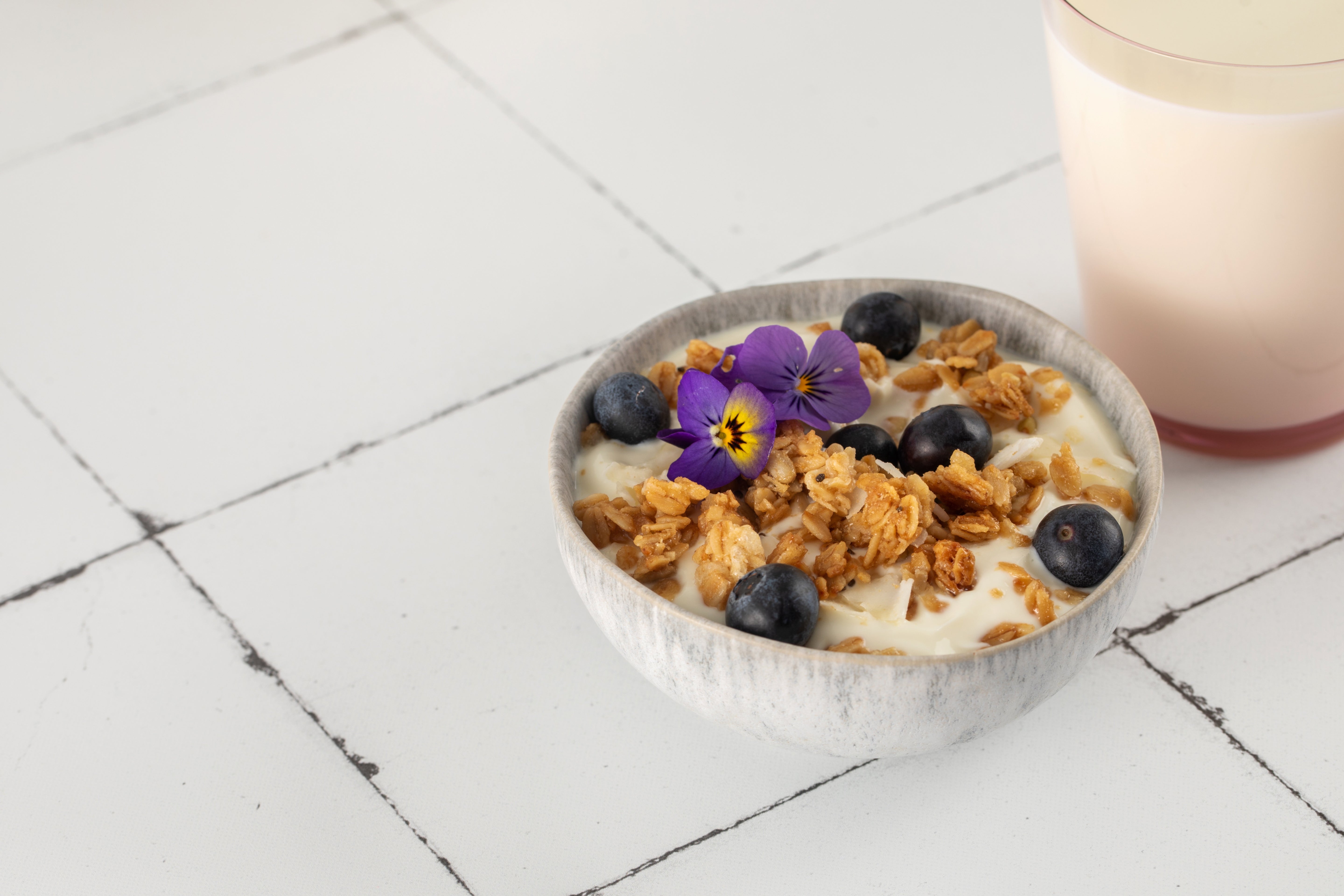 Greek yogurt parfait with granola, blueberries, edible flowers, ARLO culinary argan oil, and Manuka honey for a nourishing breakfast