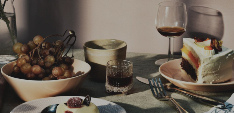 Elegant dessert table with grapes, cake, and wine glasses in soft afternoon light, evoking a refined Mediterranean dining experience
